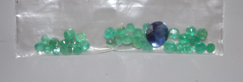 Approximately twelve carats of unmounted round cut emeralds and a round cut synthetic sapphire.